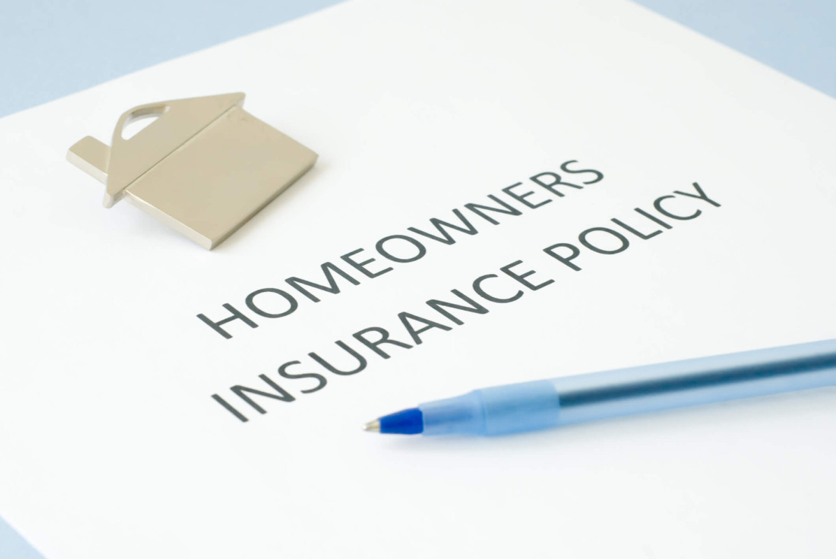 Document d’assurance habitation posé sur une table avec un stylo bleu et un porte-clés en forme de maison, symbolisant la protection du logement.