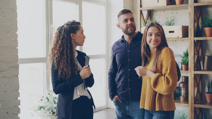 Trois personnes discutant dans salon lumineux, image illustrant la vente d’un appartement déjà occupé par des locataires.