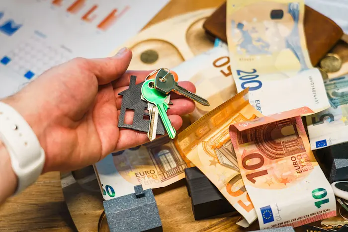 Clés de maison posées sur billets et pièces, image claire d’un prêt immobilier et gestion budgétaire.