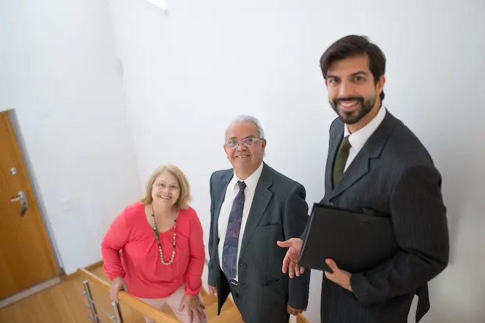 Trois personnes en tenue professionnelle discutant sur escalier moderne, symbole des démarches pour investir en France après sa retraite.