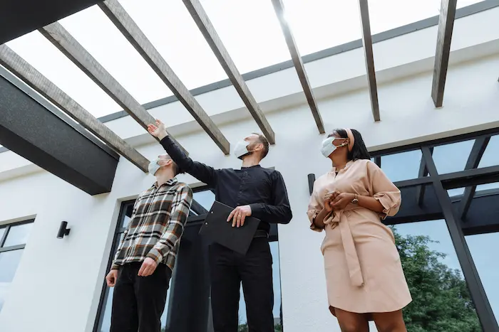 Trois personnes masquées observant une structure reflétant la vigilance et la rigueur nécessaires pour un investissement immobilier.
