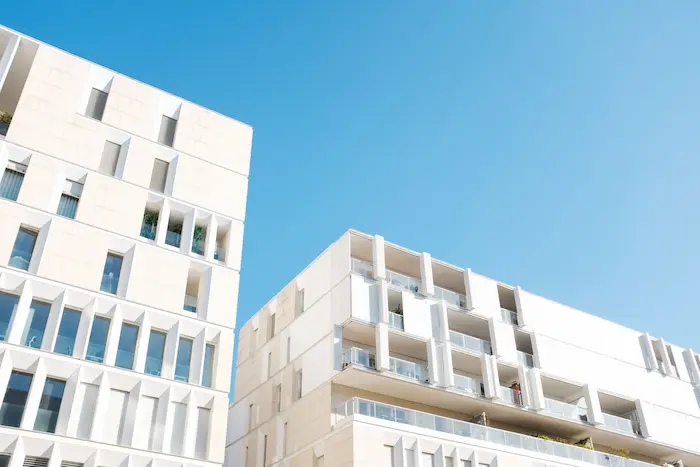 Immeubles modernes blancs sous ciel bleu, image illustrant l’investissement immobilier et l’achat d’immeuble en zone urbaine.