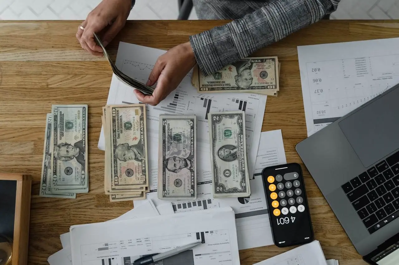 Un investisseur tient des billets dans ses mains, symbolisant les gains réalisés grâce à une gestion optimisée de l'impôt SCI, permettant une meilleure rentabilité de sa société immobilière.