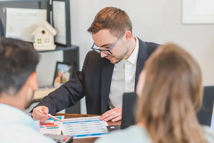 Trois personnes réunies autour d’un bureau avec graphiques financiers, reflet d’un calcul de rendement locatif