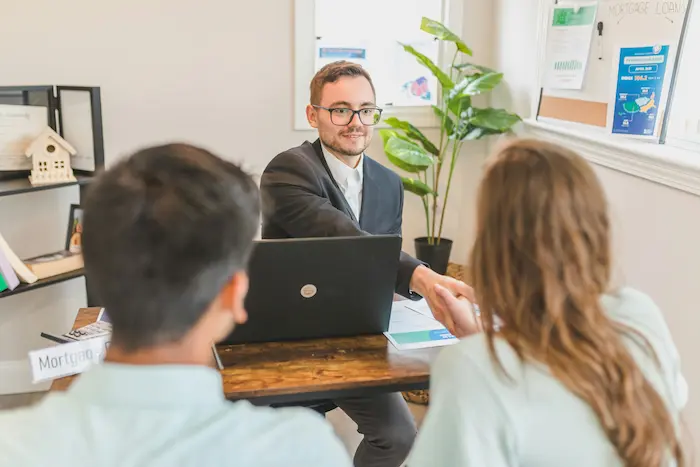 Conseiller en costume serrant la main d’un client, image illustrant le rôle du courtier en prêt immobilier.