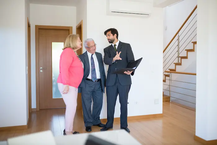 Trois personnes dans un intérieur moderne, discussion autour d’un logement vide, illustrant le principe de louer nu dans un cadre professionnel.